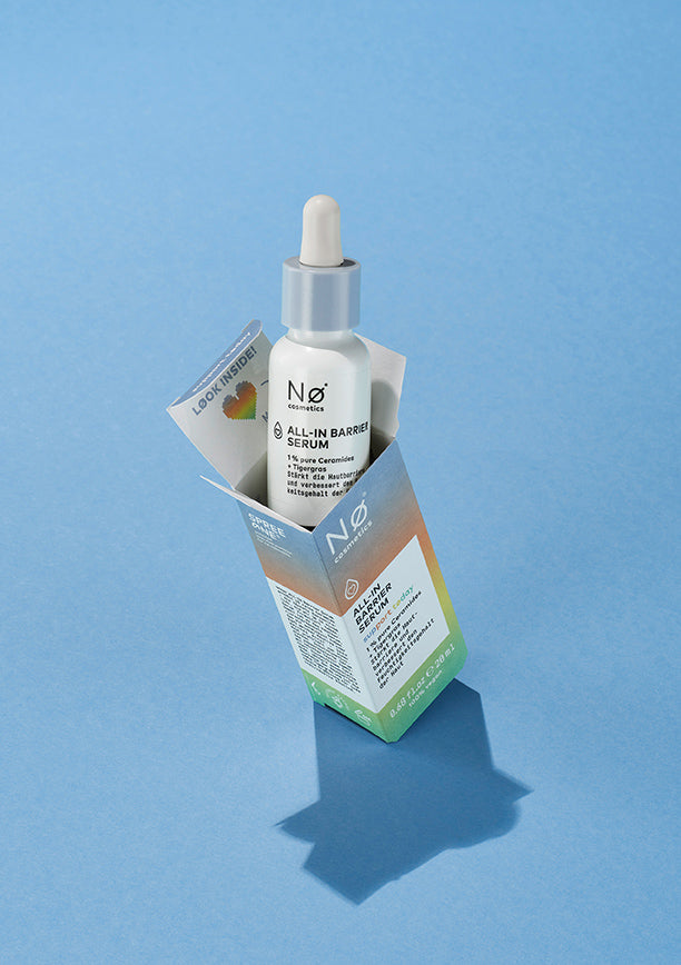 Ein Serum mit blauem Deckel, welches zu der  ALL-IN Family von Nø Cosmetics gehört, schaut aus der Umverpackung raus.