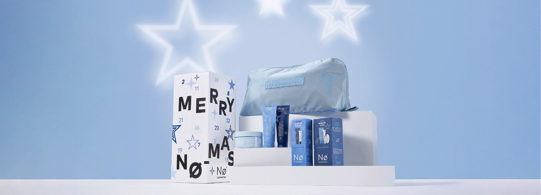 Nø Cosmetics Adventskalender mit Limited Editions auf einem Podest mit Stern-Icons auf blauem Hintergrund, Desktop Banner.