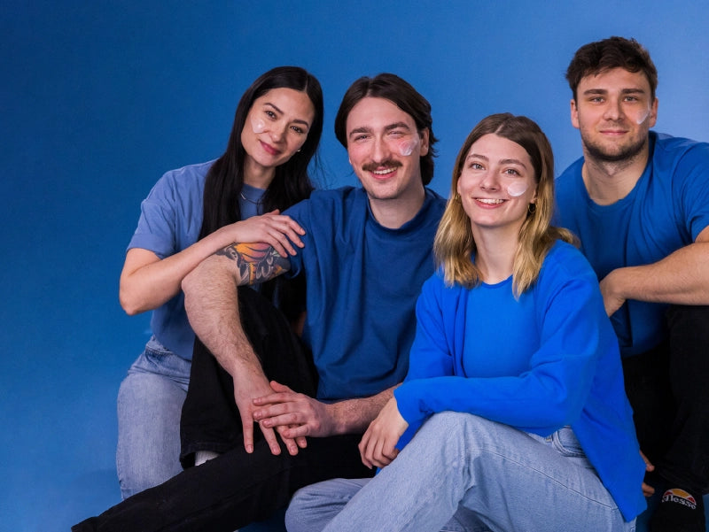 Vier lächelnde Personen mit Creme im Gesicht.