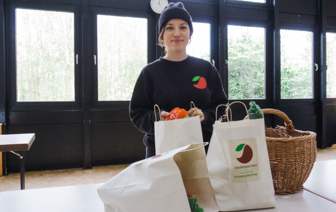 Eine junge Frau packt Tüten in der Obstkaeppchen-Zentrale.