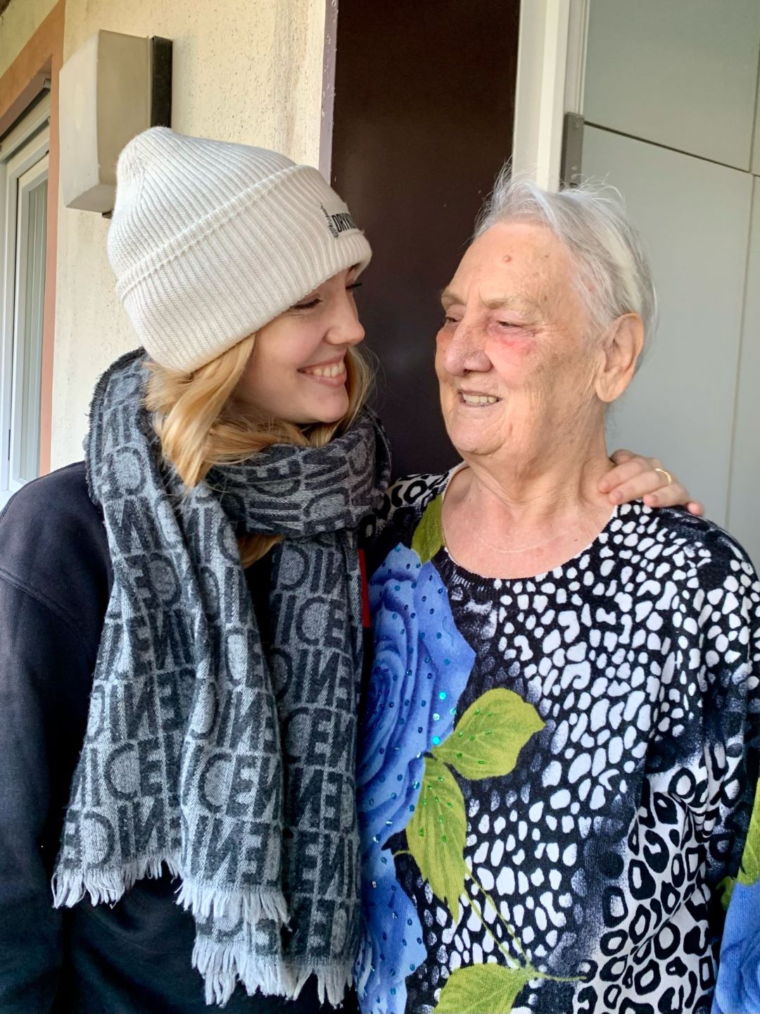 Eine junge Frau hält eine Seniorin im Arm.