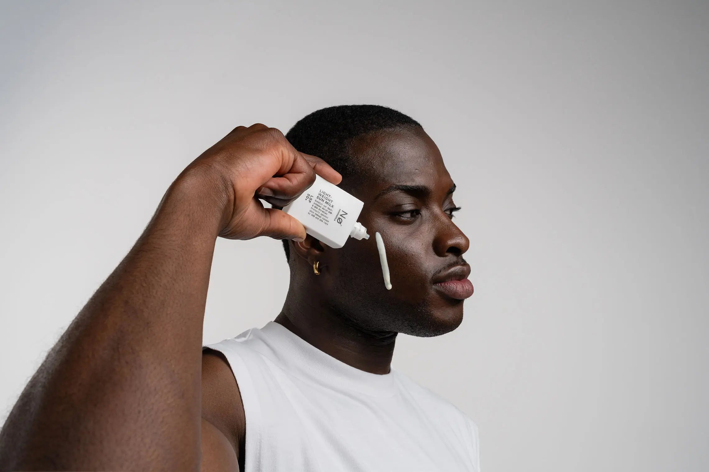 Person mit der Lightweight Sun Milk von Nø Cosmetics