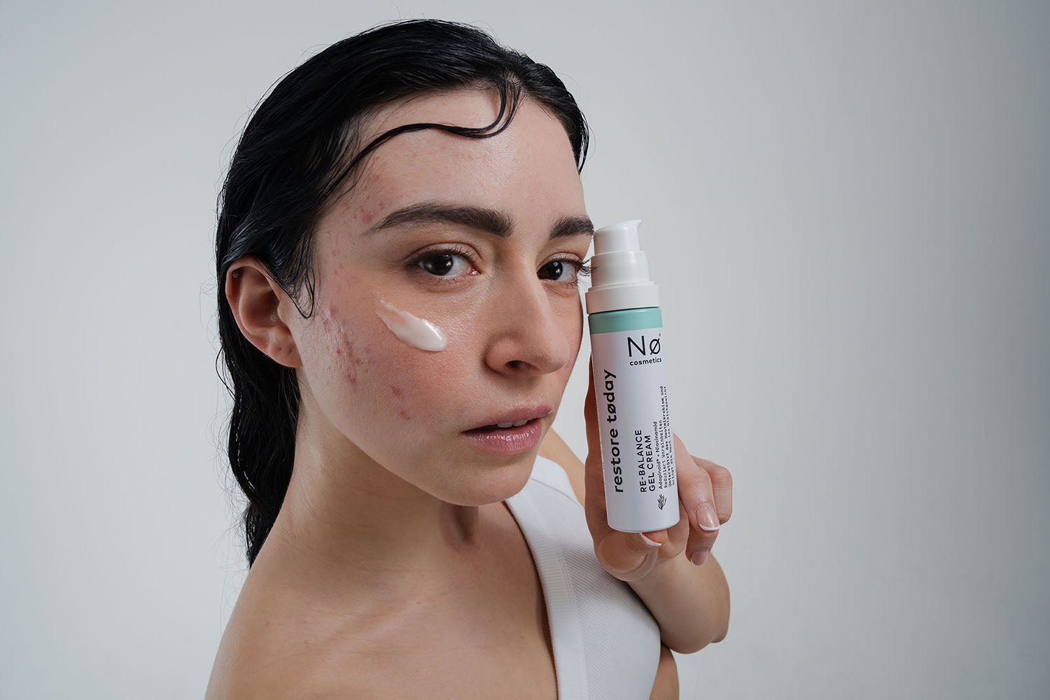 Person hält die Re-Balance Gel Cream restore tøday neben dem Gesicht.