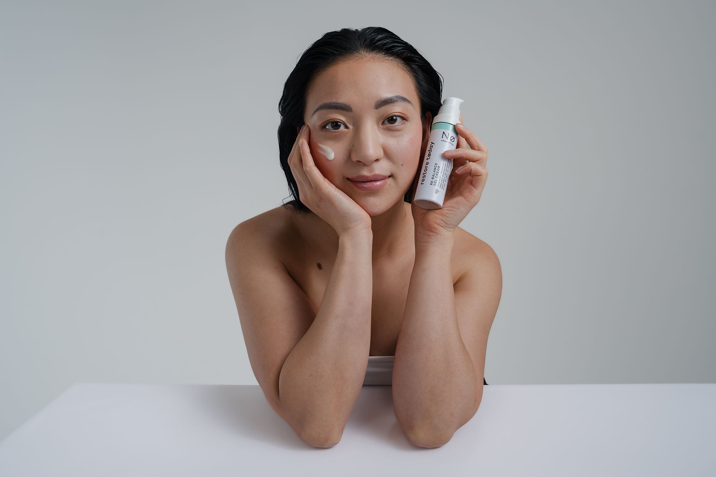 Person hält die Re-Balance Gel Cream restore tøday neben dem Gesicht